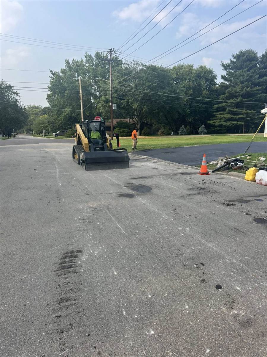 Skid steer moving into position on a street repair job