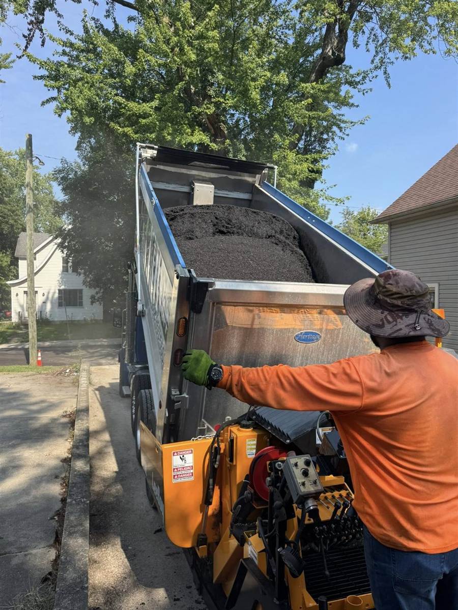Paul's Asphalt Paving crew loading hot mix into the paver on a Fort Wayne jobsite